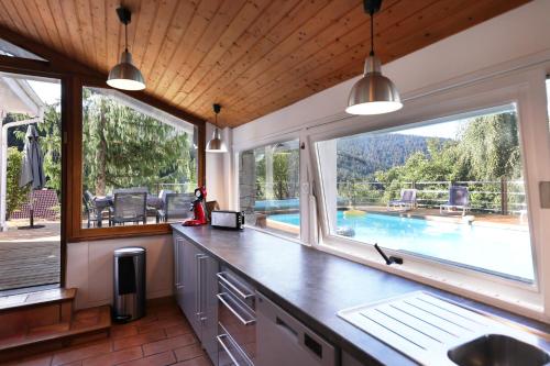 une cuisine avec fenêtres et vue sur la piscine dans l'établissement LE CHALET BLANC - JACUZZI / PISCINE / SAUNA, à Gérardmer