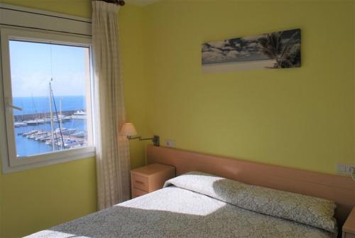 um quarto com uma cama e uma grande janela em Duplex Residencial Marina del Port 72 em Calafat