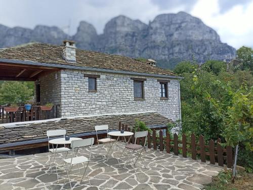 a patio with chairs and a building with mountains in the background at Agriogido - Rupicapra Guest Ηouse in Papigko