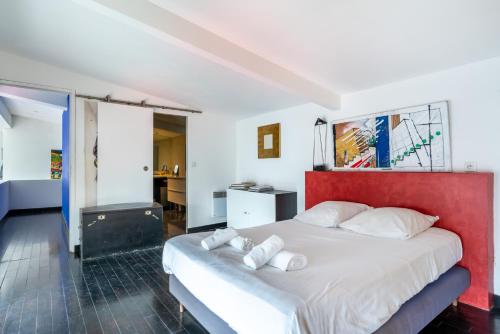 une chambre avec un grand lit avec une tête de lit rouge dans l'établissement Loft d'artiste au coeur du quartier Zola (2 pers.), à Nantes
