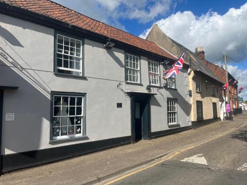 a white building with an american flag on a street at Stylish Historic Apartment - Sleeps 3 & Parking in Norwich