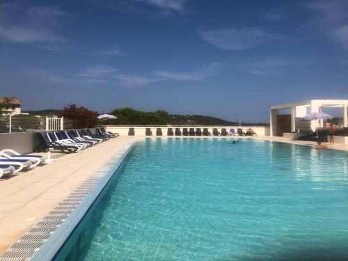 - une piscine d'eau bleue et des chaises longues dans l'établissement Charmante petite maison dans résidence avec piscine chauffée à 600 m de la plage, à Belgodère