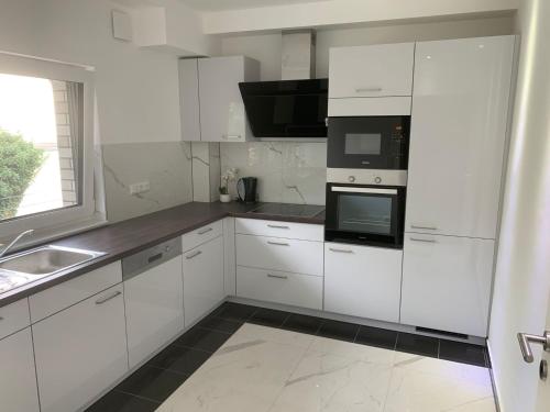 a white kitchen with white cabinets and black appliances at AT-Rooms in Hannover
