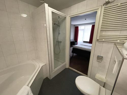 a bathroom with a tub and a toilet and a shower at Van der Valk Hotel De Molenhoek-Nijmegen in Molenhoek