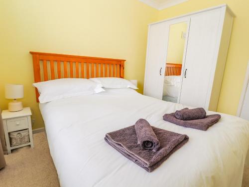 a bedroom with a white bed with towels on it at Crummock in Frodsham