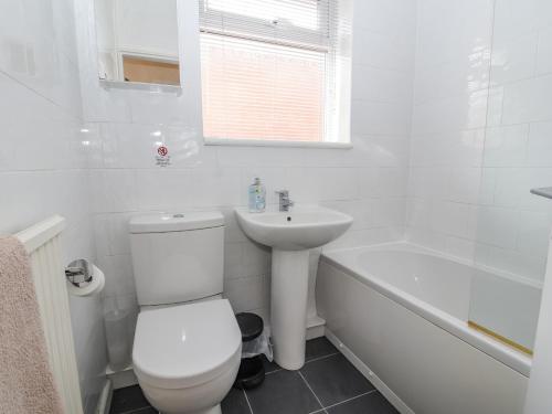 a white bathroom with a toilet and a sink at Crummock in Frodsham