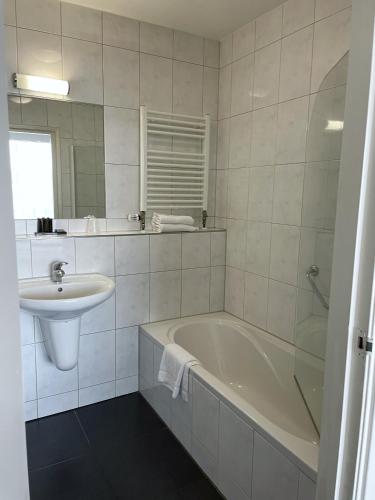 a white bathroom with a tub and a sink at Van der Valk Hotel De Molenhoek-Nijmegen in Molenhoek
