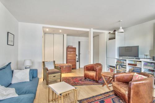 ein Wohnzimmer mit einem Sofa, Stühlen und einem TV in der Unterkunft Superb flat with terrace nearby the Eiffel Tower - Welkeys in Paris