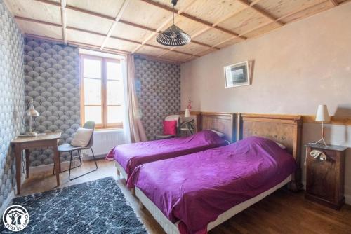 a bedroom with a purple bed and a chair at La maison des archers in Saint-Saturnin