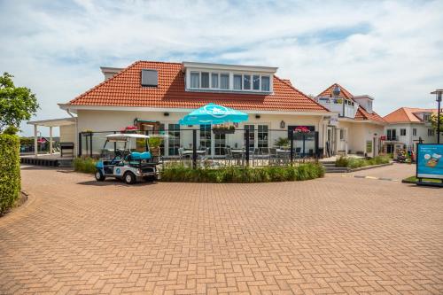 a house with an umbrella and a golf cart in front of it at EuroParcs Noordwijkse Duinen in Noordwijk aan Zee