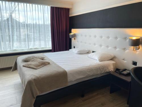 een slaapkamer met een groot bed met een wit hoofdeinde bij Van der Valk Hotel De Molenhoek-Nijmegen in Molenhoek