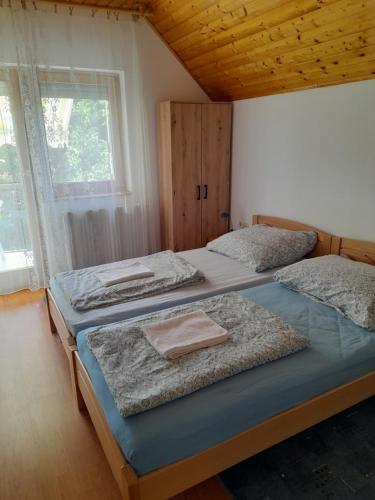 two twin beds in a room with a window at Ilona Vendégház Balatonszabadi in Balatonszabadi