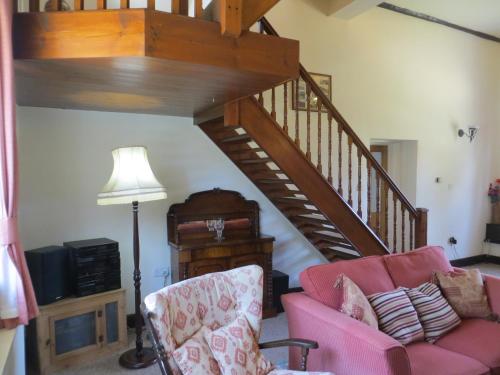 a living room with a pink couch and a staircase at The Smithy in Snettisham