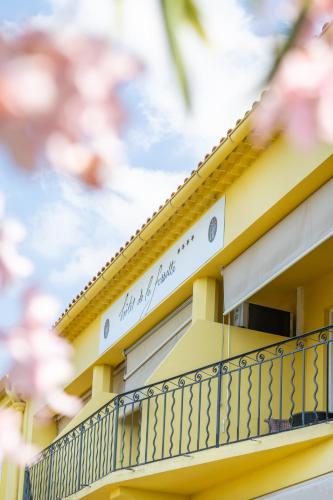 a balcony of a yellow house with a sign on it at Hôtel de La Fossette in Le Lavandou