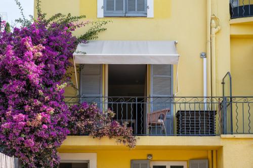 a yellow building with purple flowers on a balcony at Hôtel de La Fossette in Le Lavandou