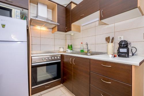 a kitchen with wooden cabinets and a sink and a refrigerator at cozy panta in Orestiada