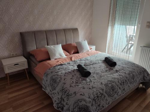 a bedroom with a bed with two black slippers on it at Dévai-LUX Apartman Sárvár in Sárvár