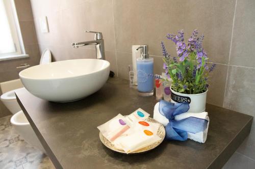baño con lavabo y encimera con aseo y flores en Il Principe rosso, en Roatto