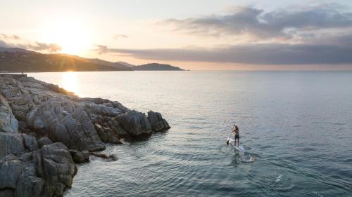 a person on a paddle board in the water at Hôtel de La Fossette in Le Lavandou