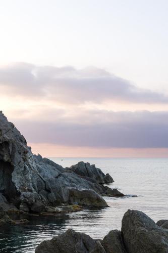 a view of the ocean with rocks in the foreground at Hôtel de La Fossette in Le Lavandou