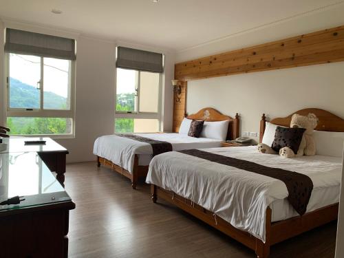 two beds in a hotel room with two windows at 山水屋民宿 in Beipu