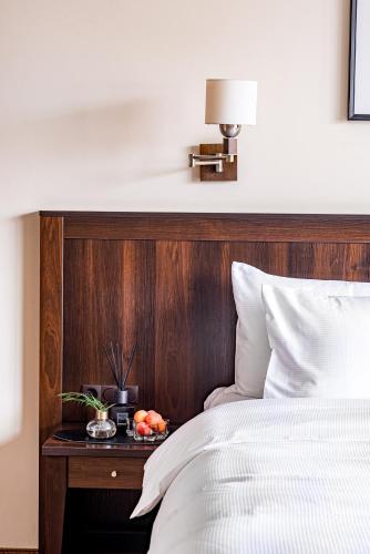 a bed with a wooden headboard and a table with fruit on it at Kerpė Hotel & SPA in Palanga