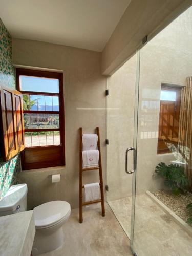 a bathroom with a toilet and a glass shower at Piña Coloradas Ecolodge in Yuluc