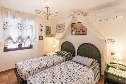 una camera con due letti e un lampadario a braccio di villa con immenso giardino a Orosei