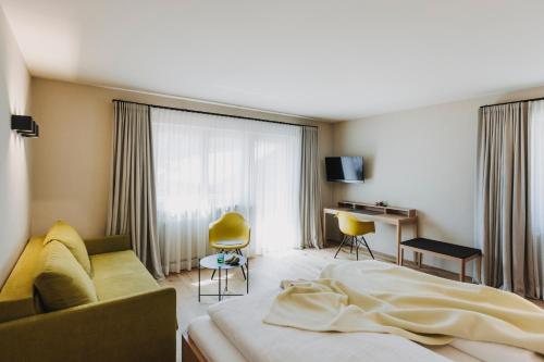 - une chambre avec un lit, un canapé et un bureau dans l'établissement Hotel Alpenrose, à Au im Bregenzerwald
