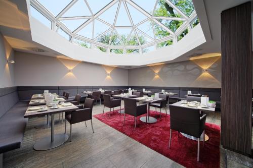 a dining room with tables and chairs and a large skylight at Hotel HerzogsPark in Herzogenaurach