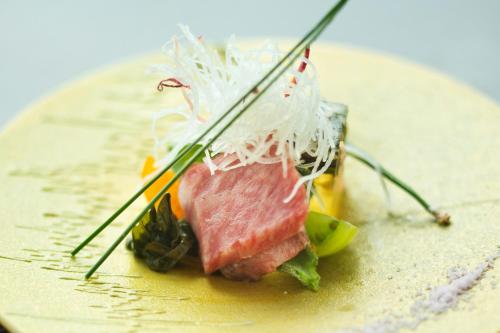 a piece of food on a plate with chopsticks at Noto Hyakurakusou in Ogi