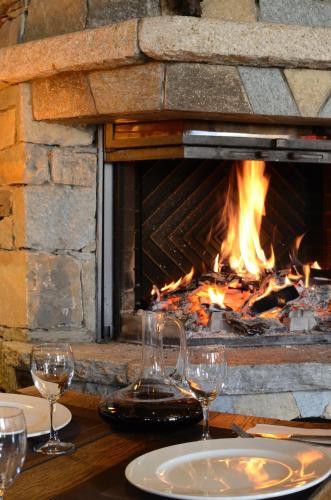 a table with wine glasses and a fireplace at Le Solan d'Aniathazze in Peisey-Nancroix