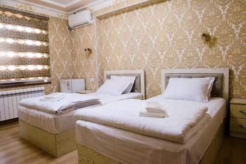 two twin beds in a room with a wall at Durdona Guest House in Samarkand