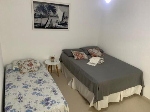 um pequeno quarto com uma cama e uma mesa em Aloha Beach Temporada em Cabo Frio