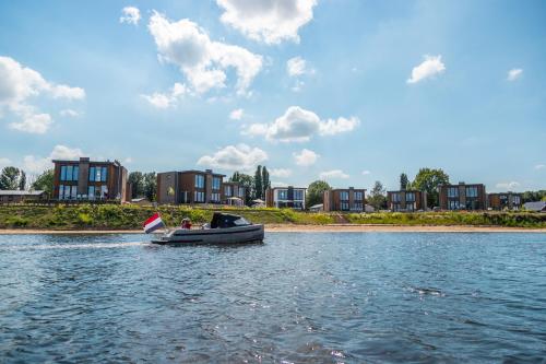 a boat on the water with buildings in the background at Vakantiepark Aan de Maas in Kerkdriel