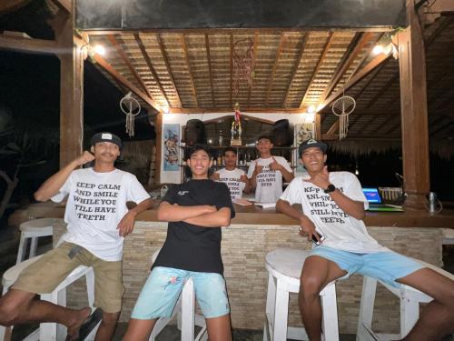 a group of men sitting on bar stools holding up signs at Gita Gili Bungalow in Gili Islands