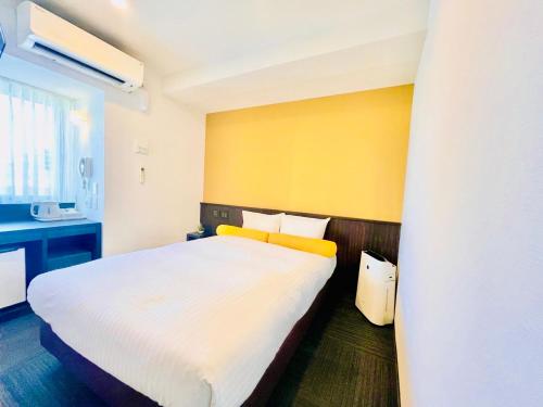 a bedroom with a white bed and a yellow wall at Nipponbashi Crystal Hotel in Osaka