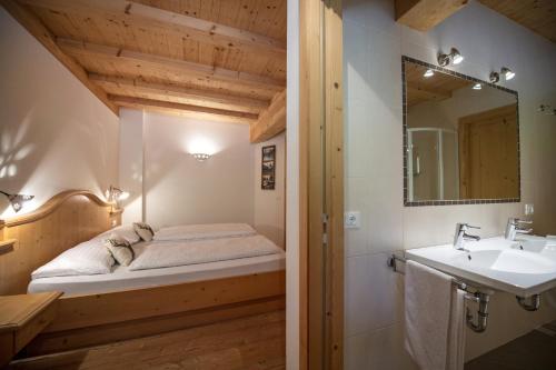 a bathroom with a bed and a sink and a mirror at Apartments Bea in Ortisei