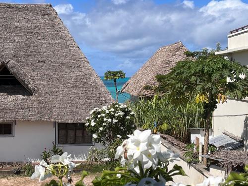 two thatched cottages with the ocean in the background at RaCoCo Villa in Jambiani