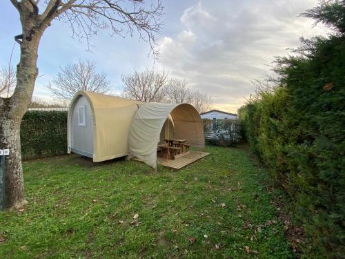 a tent with a table in a yard at Camping Le Beaulieu in Puilboreau