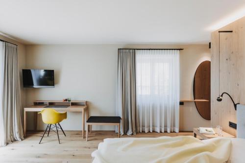 ein Schlafzimmer mit einem Bett und einem Schreibtisch mit einem gelben Stuhl in der Unterkunft Hotel Alpenrose in Au im Bregenzerwald