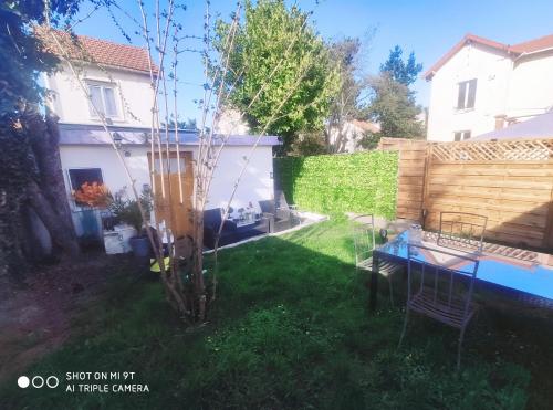 un patio trasero con un árbol y una mesa en el césped en Orly Pico studio, en Choisy-le-Roi