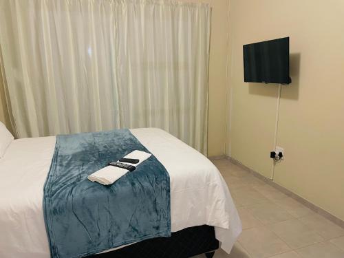 a hotel room with a bed with towels and a television at Druza’s guest house in Rustenburg