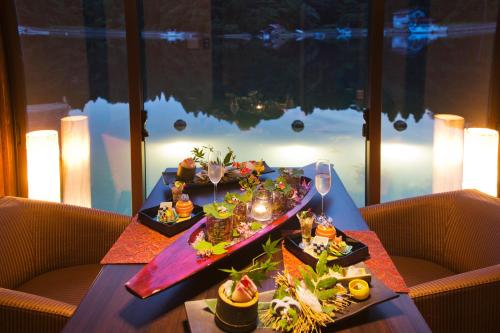 a table with two plates of food and wine glasses at Noto Hyakurakusou in Ogi