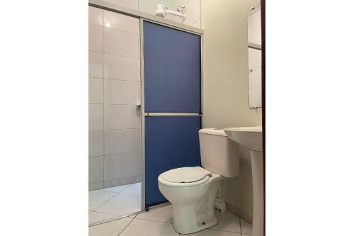 La salle de bains est pourvue de toilettes et d'une porte bleue. dans l'établissement Casa com piscina Balneario Ipanema PR, à Pontal do Paraná