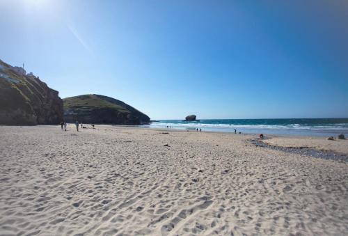 a beach with people walking on the sand and the ocean at Rosebud in Portreath