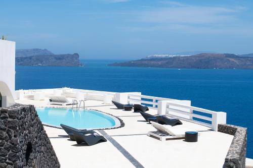 - une piscine avec des chaises longues et l'océan dans l'établissement Avant Garde Suites, à Akrotiri