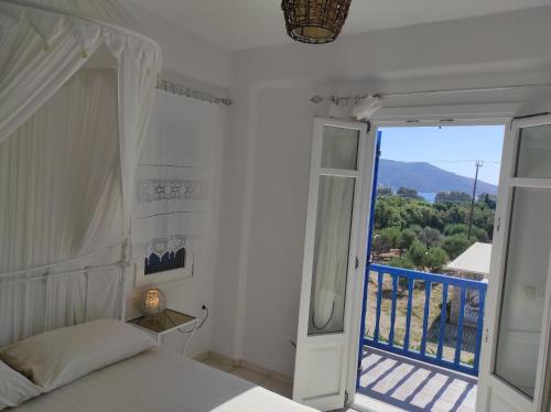 1 dormitorio con cama y vistas a un balcón en Villa Le Grand Bleu, en Katápola