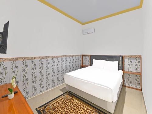 a small bedroom with a white bed and a table at OYO 91192 Homestay Antara in Gilimanuk