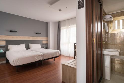 a bedroom with a bed and a tub and a sink at Hotel Alda Centro Gijón in Gijón